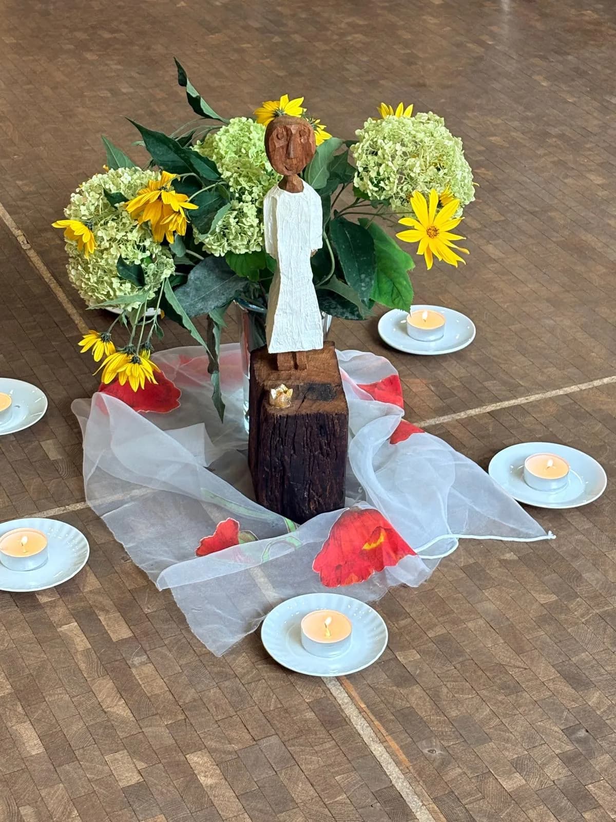 Würdekönigin aus Holz mit Blumen und Kerzen
