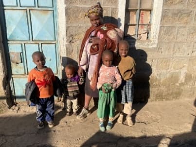 Eine Mutter mit ihren Kindern vor ihrem Zuhause in Kenia